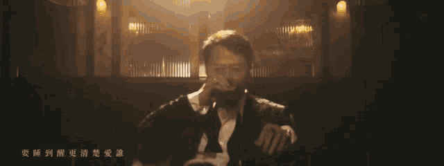 a man singing into a microphone in a dark room with chinese writing on the bottom