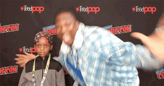 a man and a boy are standing in front of a wall that says feedpop