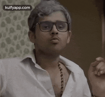 a man wearing glasses and a white shirt is making a funny face .