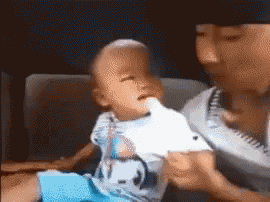 a baby is drinking milk from a bottle while being held by a person .