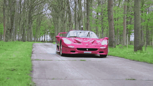 a pink ferrari is driving down a road