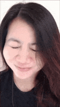 a close up of a woman 's face with her eyes closed and her hair blowing in the wind