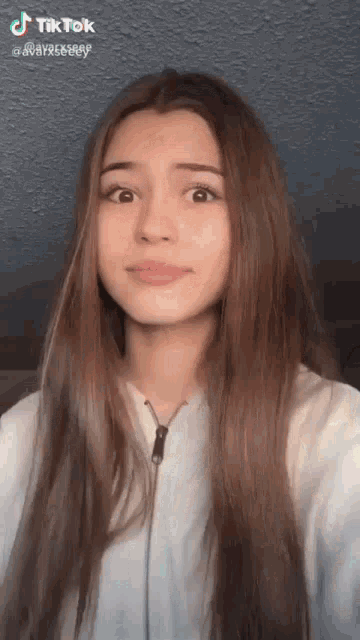 a girl with long brown hair is making a funny face while looking at the camera .