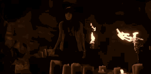 a woman is surrounded by lit candles with the letter s on the bottom