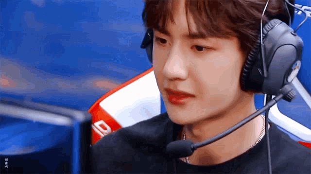 a young man wearing headphones and a microphone is sitting in front of a computer screen .