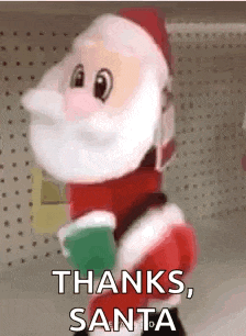 a stuffed santa claus mascot is standing in front of a wall and says `` thanks santa '' .