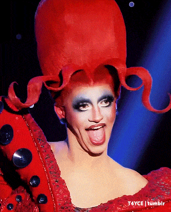 a drag queen wearing a red octopus wig and a red dress sticking her tongue out