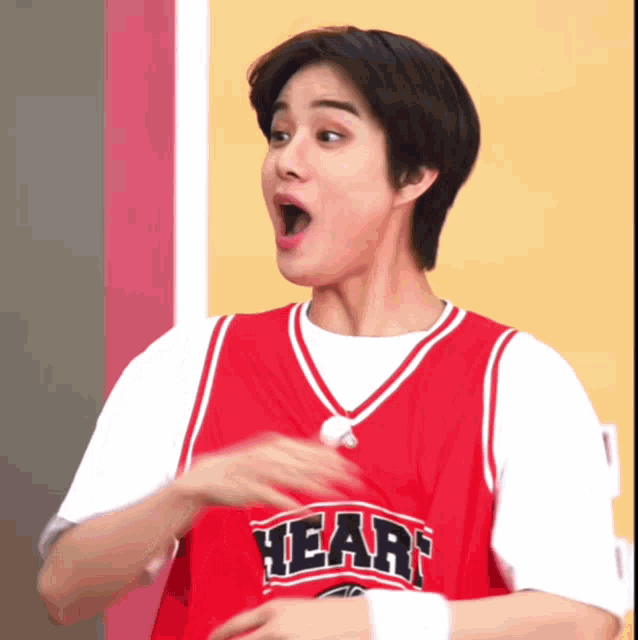 a young man wearing a red heart jersey makes a funny face