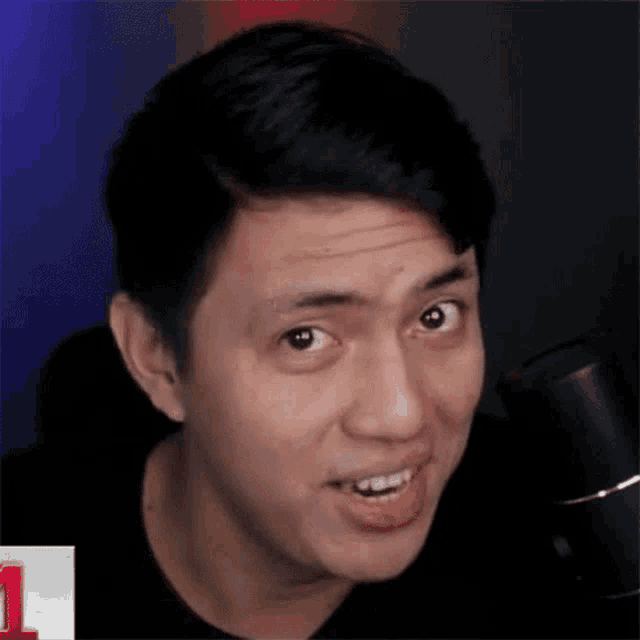a man is making a funny face in front of a microphone in a dark room .