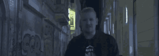 a man wearing a raiders shirt is running down a dark alleyway