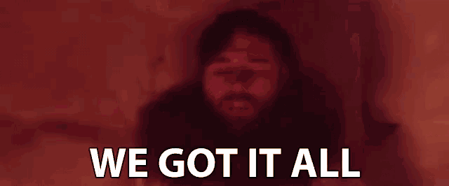 a man with a beard is laying down with his eyes closed and the words `` we got it all '' written on the bottom .