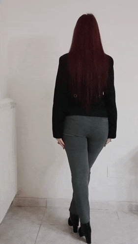 a woman with long red hair is standing in front of a white wall