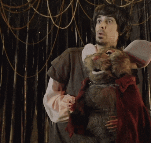 a man is holding a stuffed mouse with a red coat on