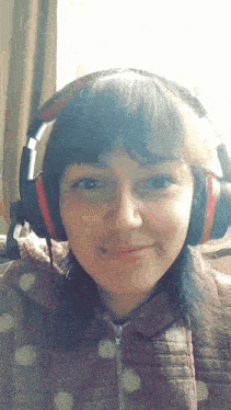 a girl wearing headphones looks at the camera and smiles