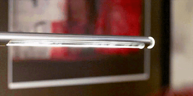 a close up of a metal object with a clock in the background and a light on it