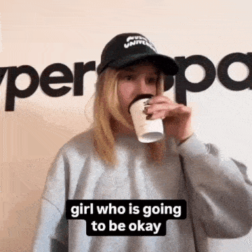 a woman wearing a hat is drinking from a cup and says " girl who is going to be okay " .