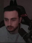 a man with a beard is sitting in front of a microphone in a chair .