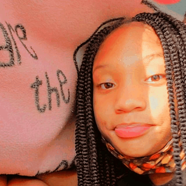 a girl with braids has the word be on her face