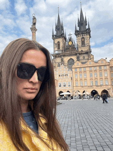 a woman wearing sunglasses stands in front of a building that says ' hotel ' on the front
