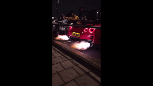 a pink car with a license plate that says lg on it is parked on the side of the road at night .