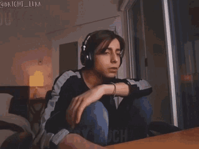 a man wearing headphones is sitting on a bed and says i love you very much .