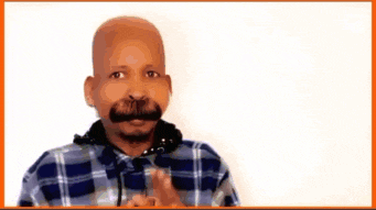 a bald man with a mustache is wearing a plaid shirt and making a funny face .