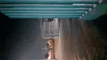 a fence is visible in the dark with a few cars parked in front of it