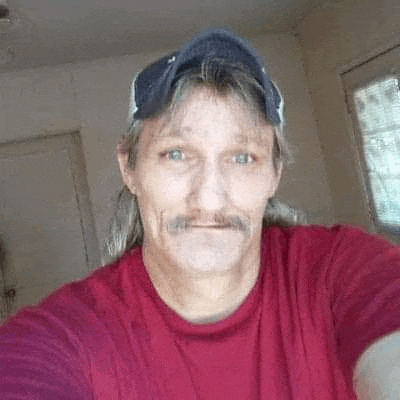 a man is taking a selfie in a red shirt and hat .