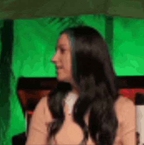a woman with long black hair and blue streaks is sitting in front of a green wall .