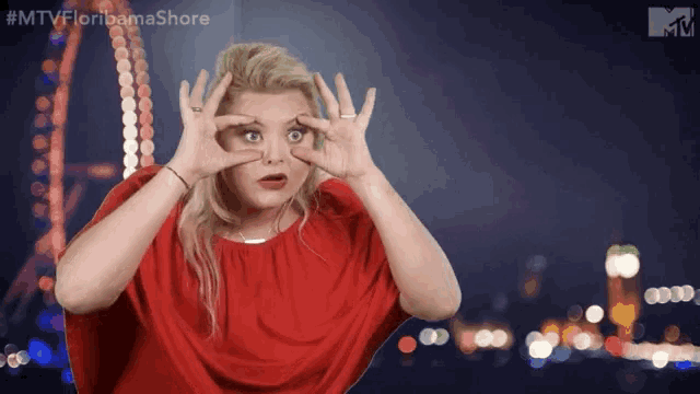 a woman in a red dress making a funny face with her hands .
