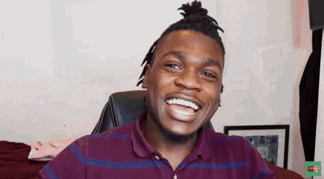 a man wearing a maroon and blue striped shirt is smiling for the camera