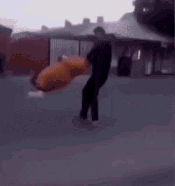 a blurry picture of a person standing on a sidewalk holding a bag .
