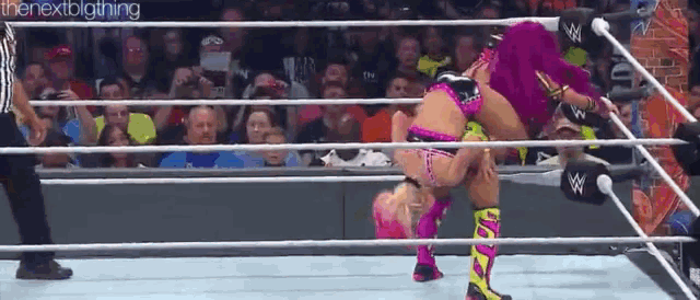 two women are wrestling in a wrestling ring with a referee watching .