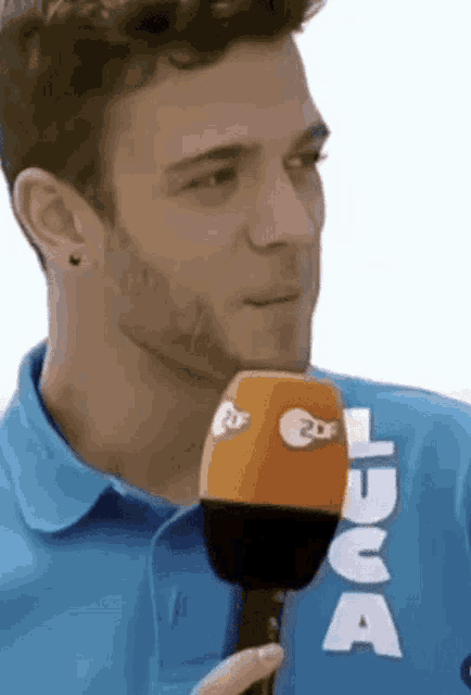 a man in a blue shirt is holding a microphone with the letter a on it
