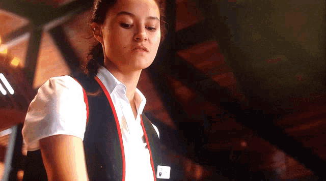 a woman wearing a white shirt and a black vest with a red stripe around the waist