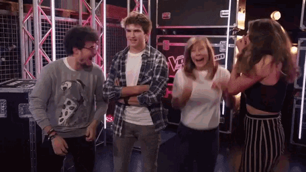 a group of people are standing in front of a box that says the voice on it