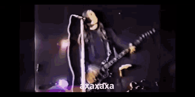 a man with long hair is playing a guitar and singing into a microphone with the word axxaxa on the bottom