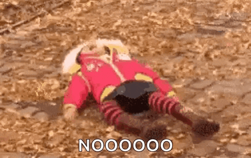 a person in a red jacket and striped pants is laying on their back on the ground .