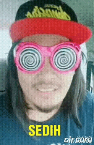 a man wearing a hat and pink hypnotic glasses with the word sedih in yellow