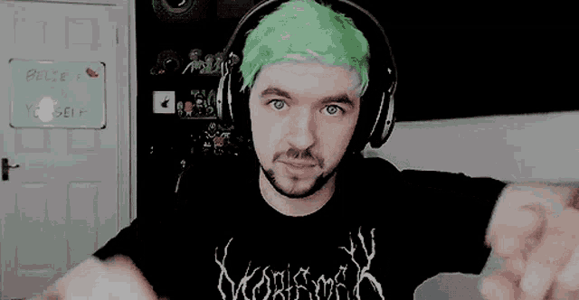a man with green hair is wearing headphones and a t-shirt that says ' believe yourself ' on it