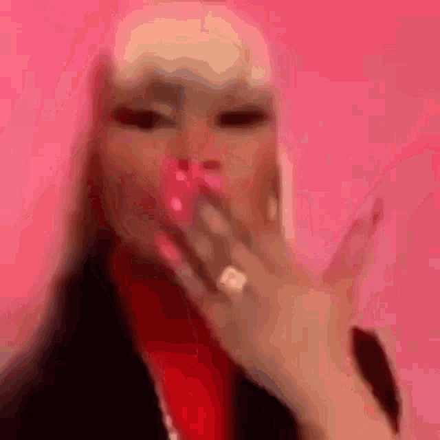 a close up of a woman blowing a kiss while wearing a ring on her finger .