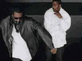 two men are dancing together and one is wearing a leather jacket .