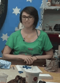 a woman sitting at a table with a mcdonald 's cup