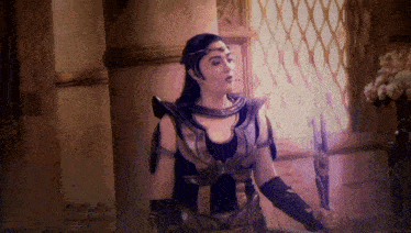 a woman in a costume is holding a sword in a room next to a window .