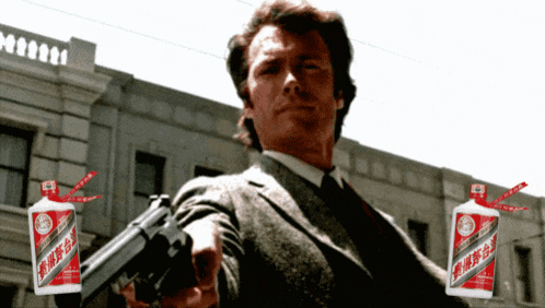 a man in a suit holds a gun in front of two bottles of alcohol