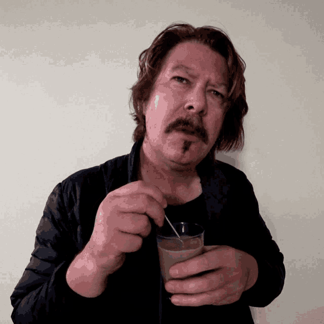 a man with a mustache is drinking from a glass