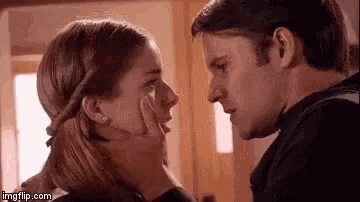 a man and a woman are touching each other 's faces and looking at each other .