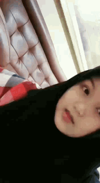 a young girl wearing a black hijab is sitting on a couch .