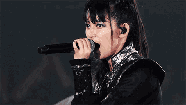 a woman singing into a microphone with ear buds on her ears