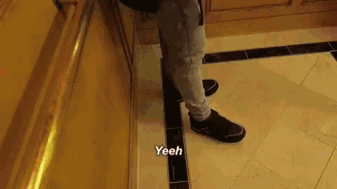 a person is standing on a tiled floor with the words yeeh written on the floor .